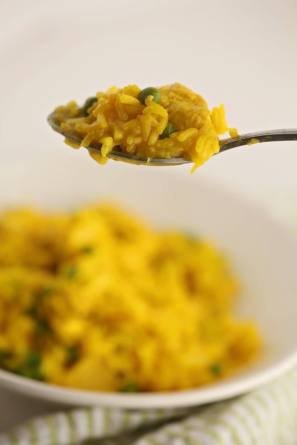 full spoon of bright colored rice with peas and turmeric