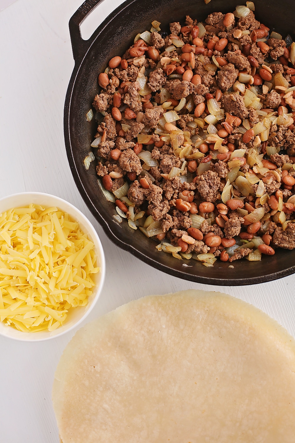 tabletop with skillet with browned meat and tortillas