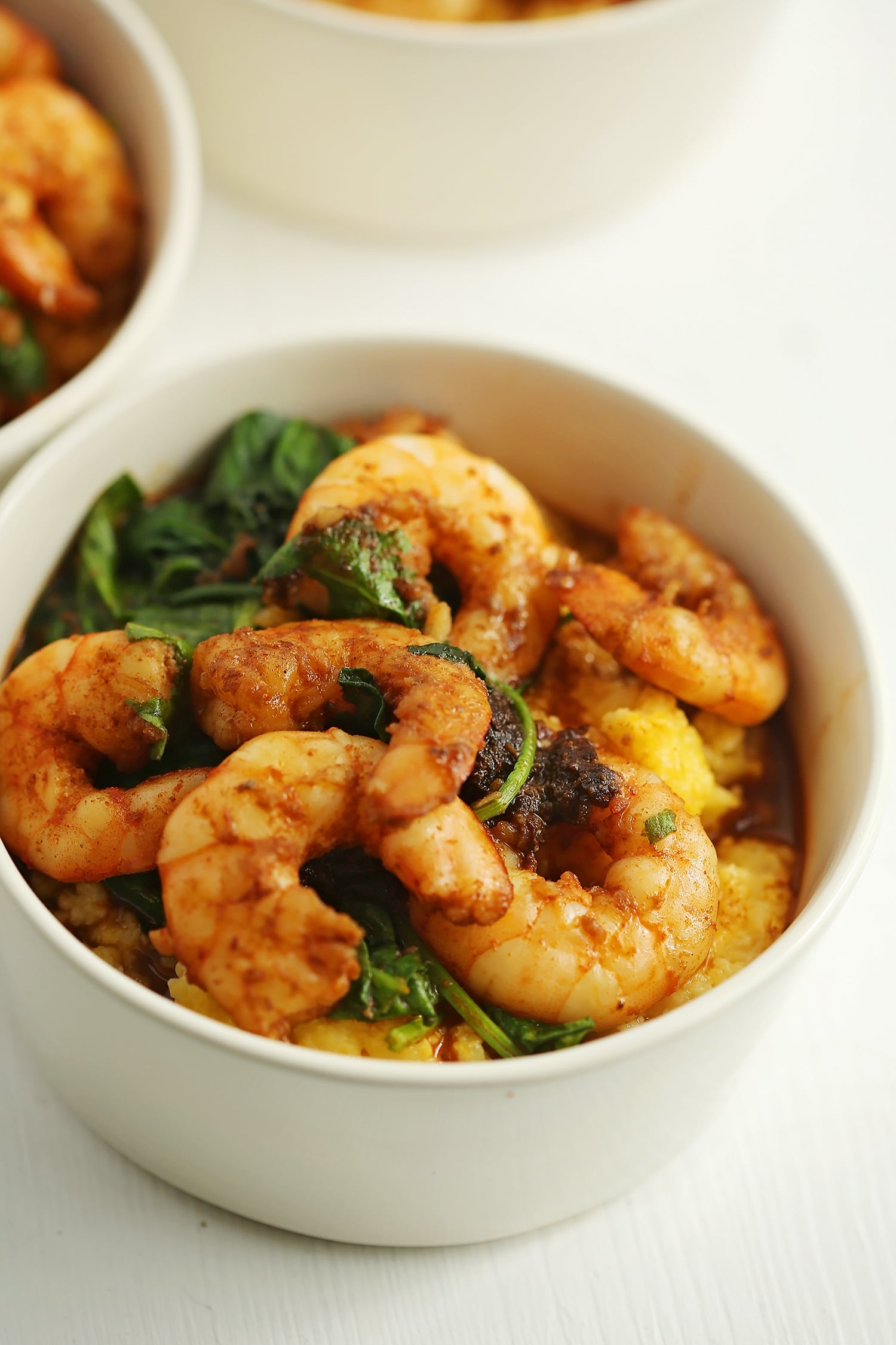 shrimps, grits, and spinach in a white bowl