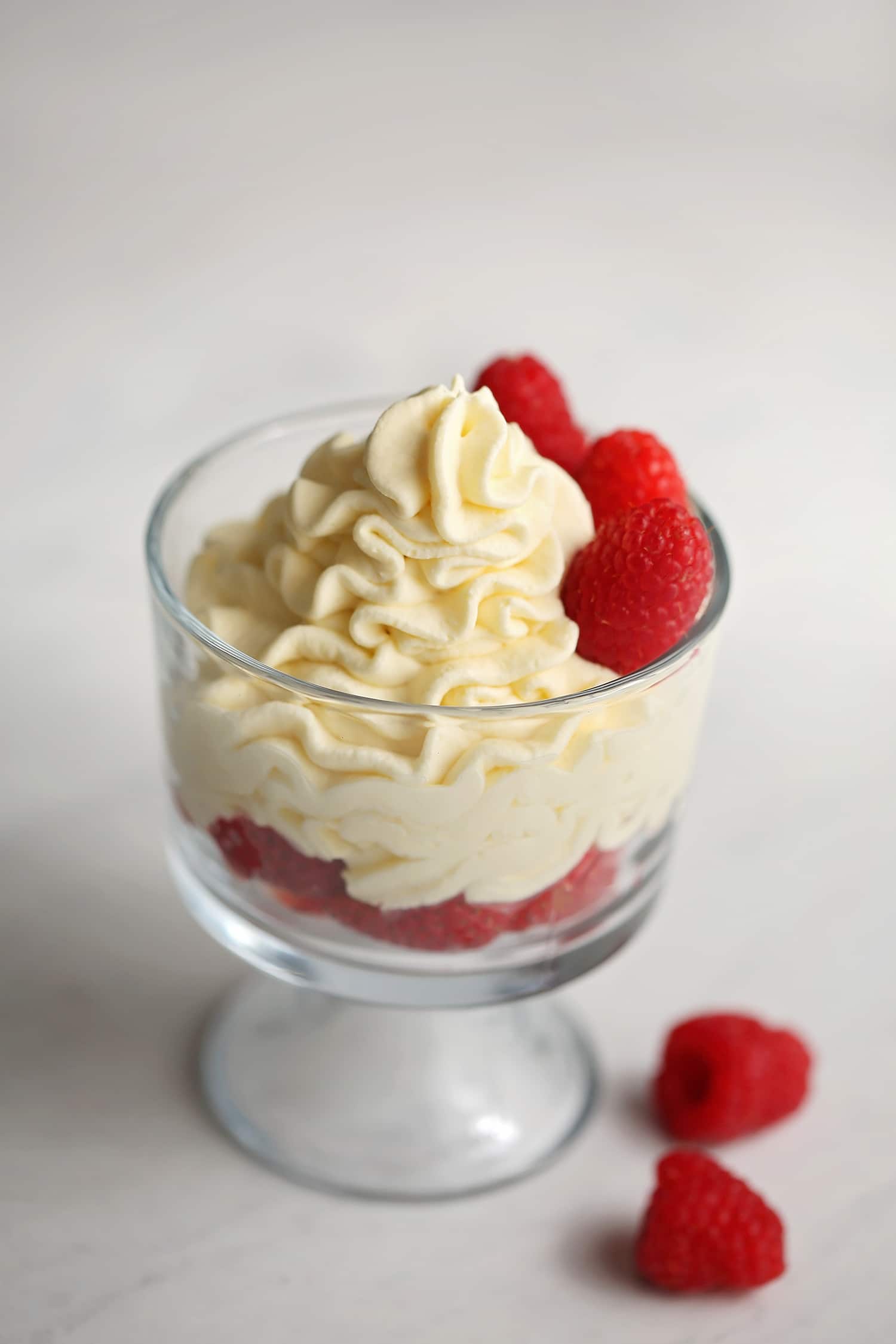 homemade whipped cream served in a glass with raspberries