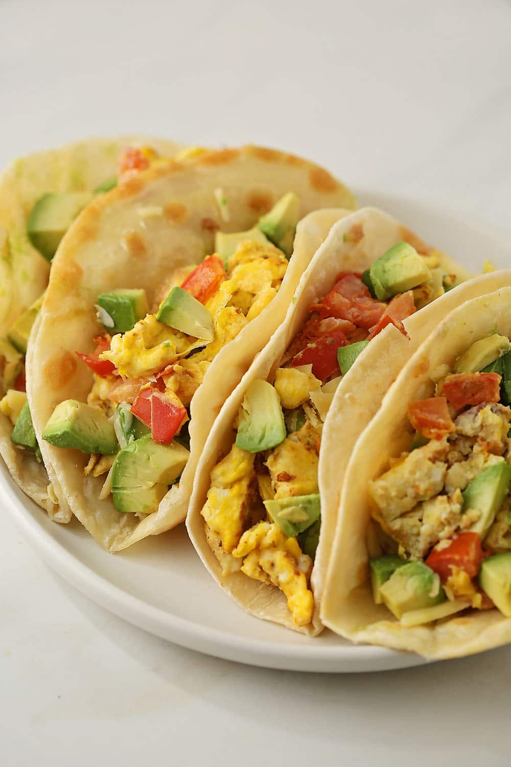 plate with tacos filled with scramble eggs and avocado