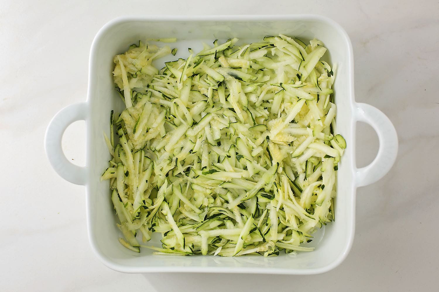 shredded zucchini in the white square dish