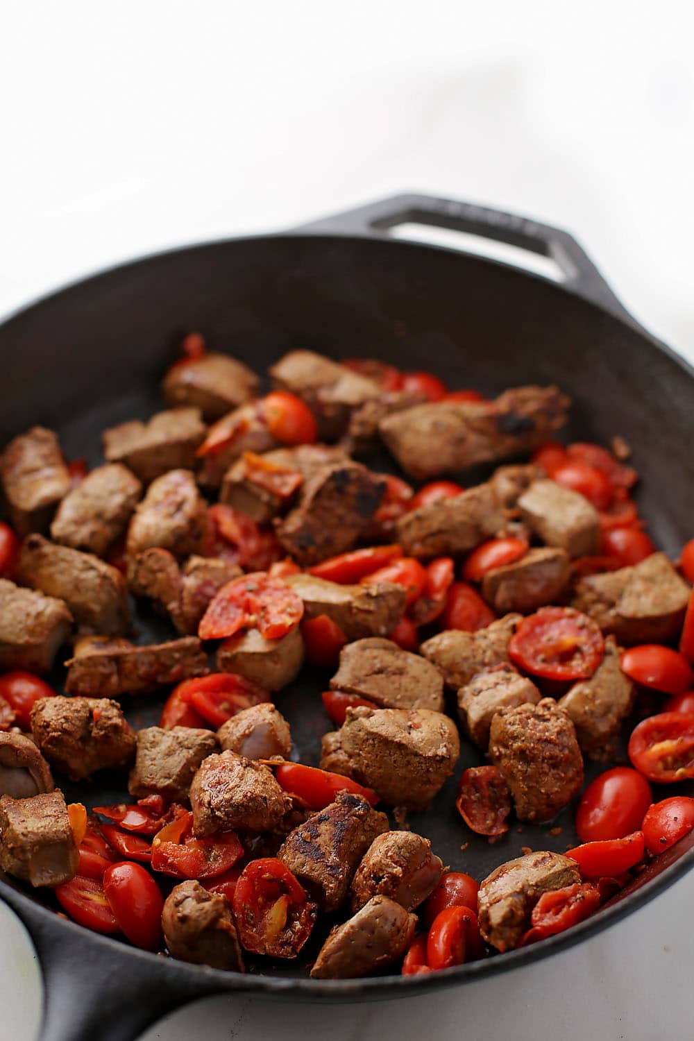 skillet with fried liver and tomatoes