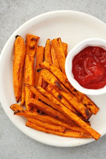 sweet potato fries on the white plate with ketchup in the small dish