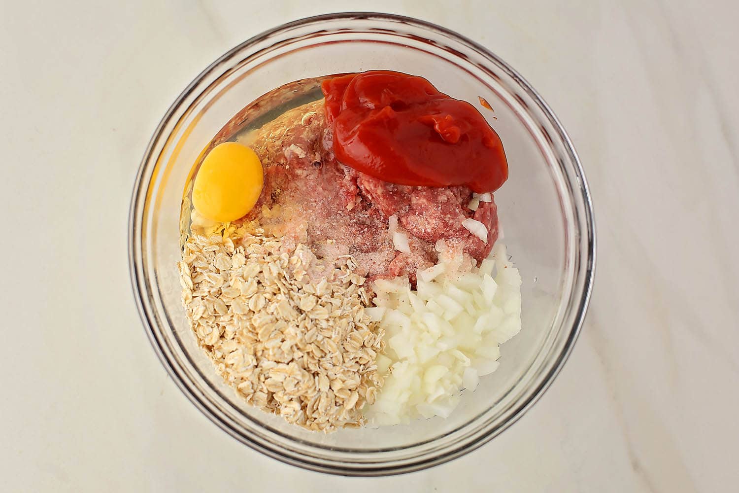 mixing bowl with ground beef, onions, oats and egg