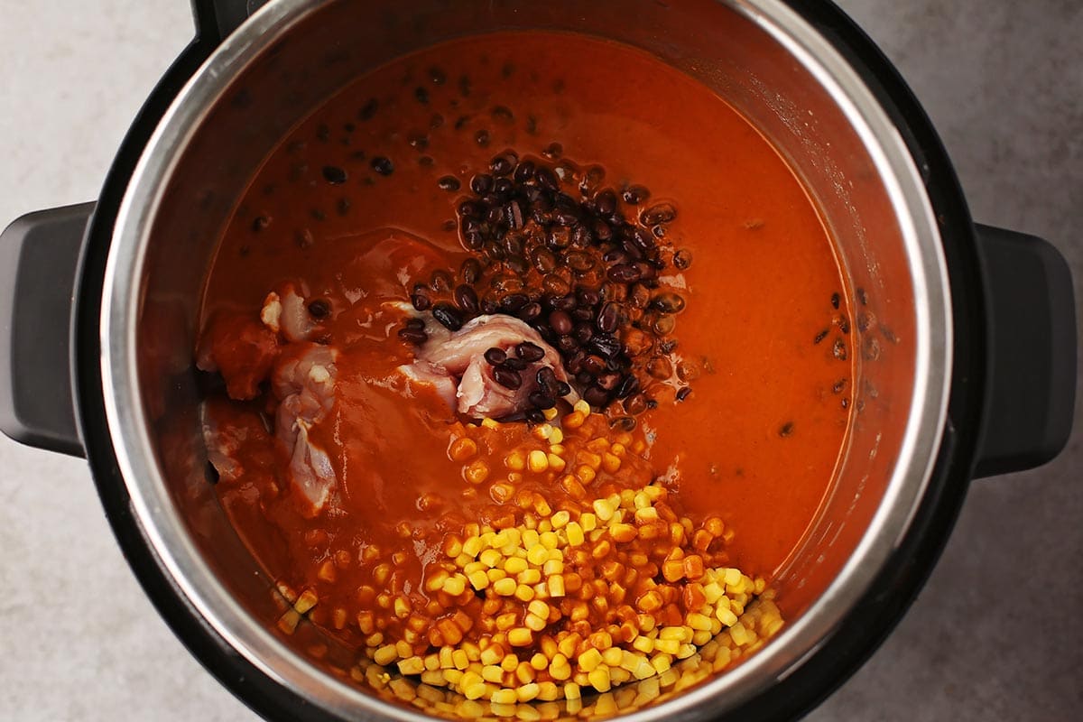 an instant pot filled with red sauce, beans, corn