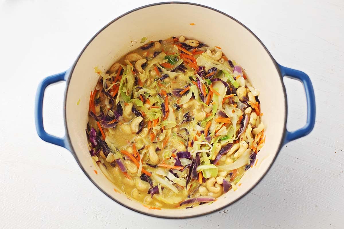 ducth oven pot filled with colorful mix of noodles, cabbage and carrots