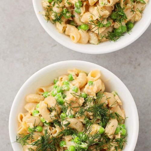 two white bowls with pasta and peas