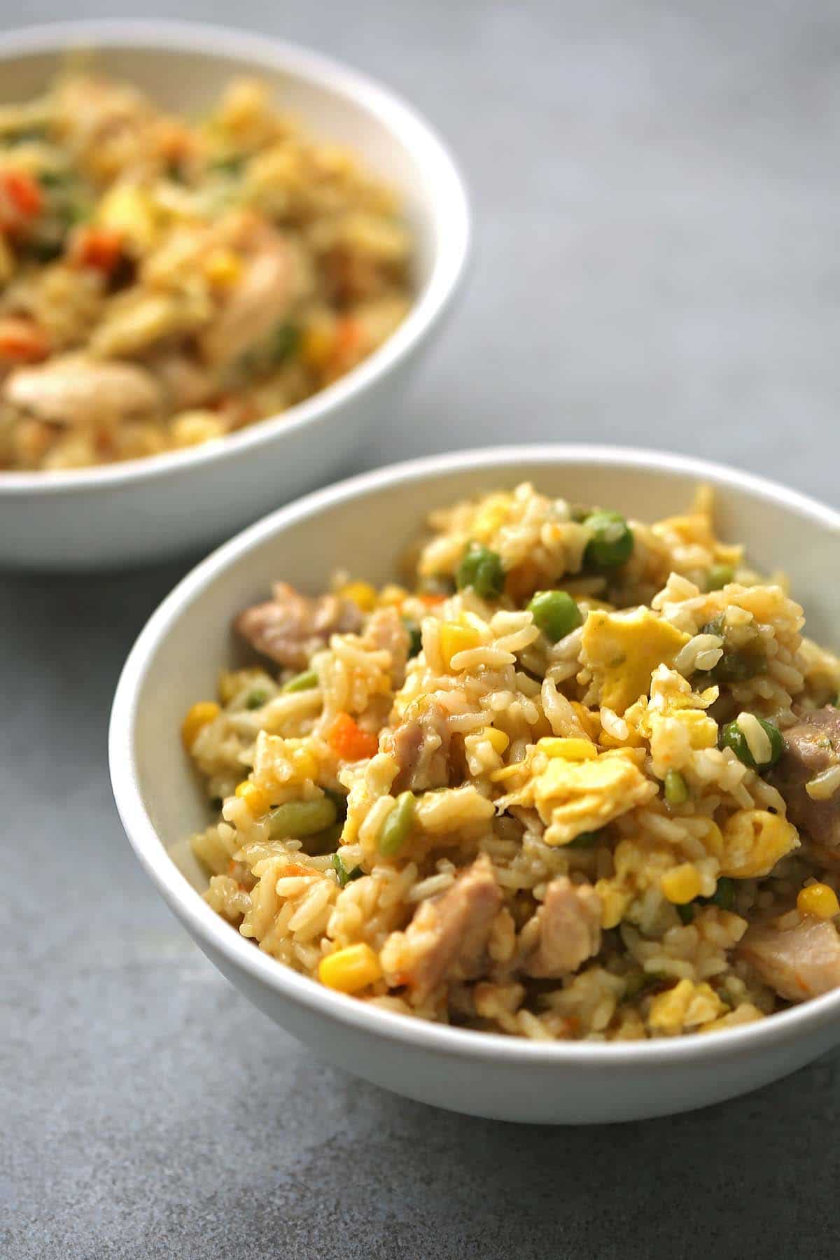 two white bowls with fried rice and vegetables