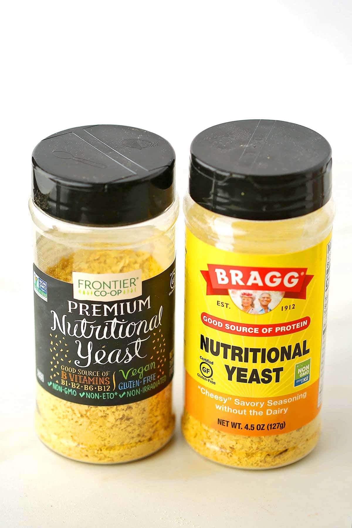 Close up image of the two containers of different brand of nutritional yeast. 