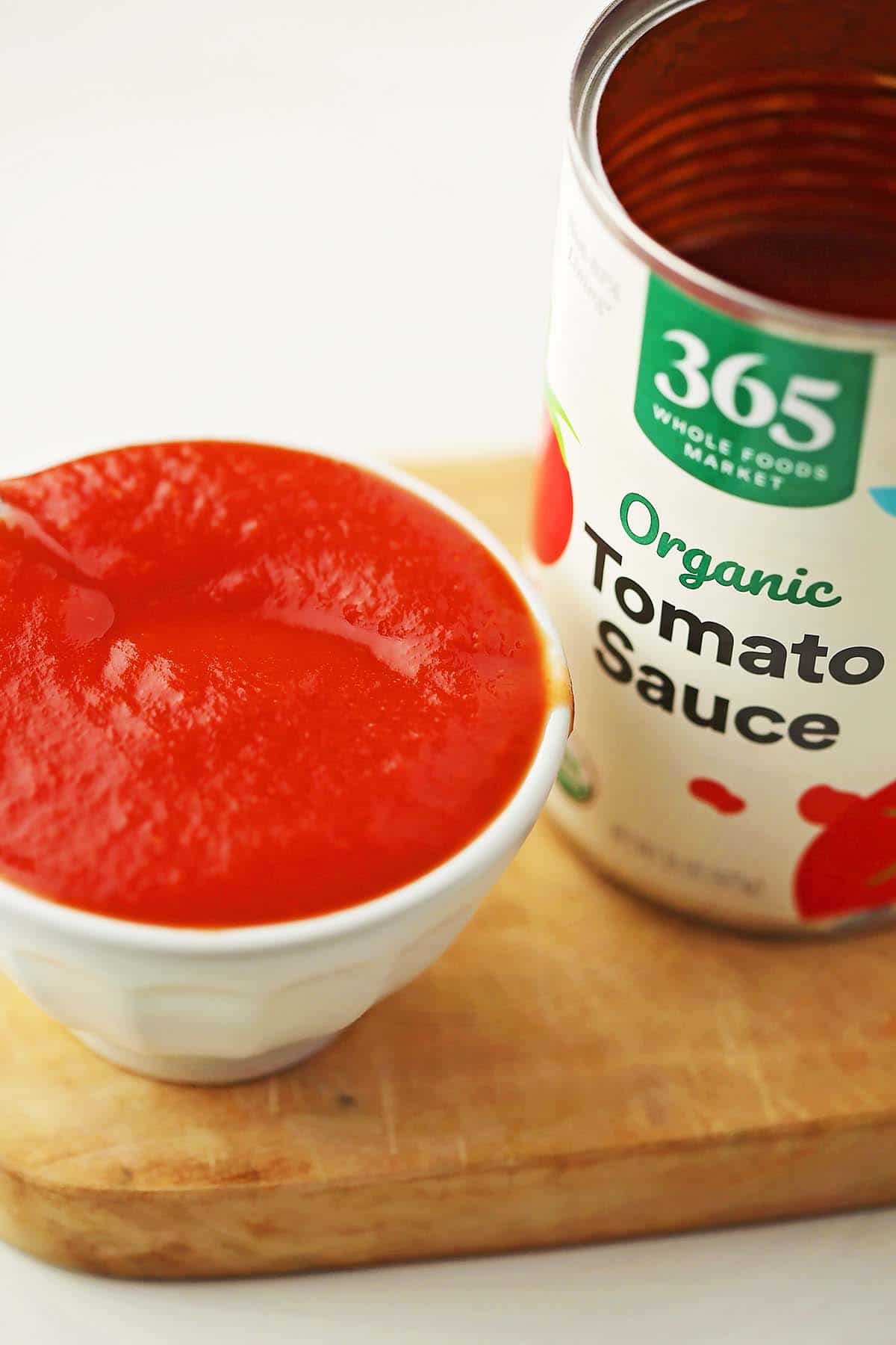 bowl filled with bright red sauce and open can labeled tomato sauce