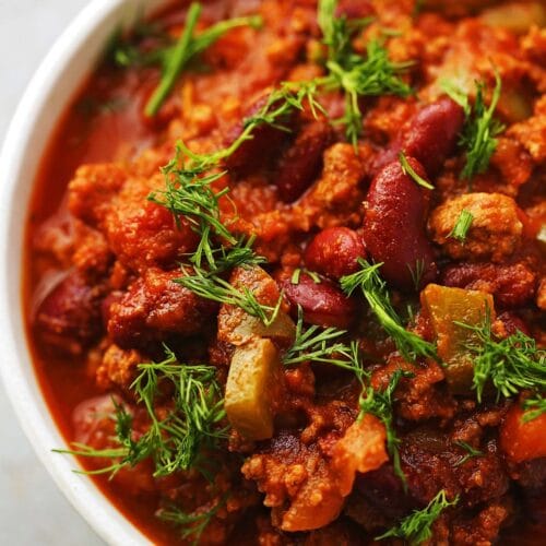 white bowl filled with meat sauce, red kidney beans and fresh dill