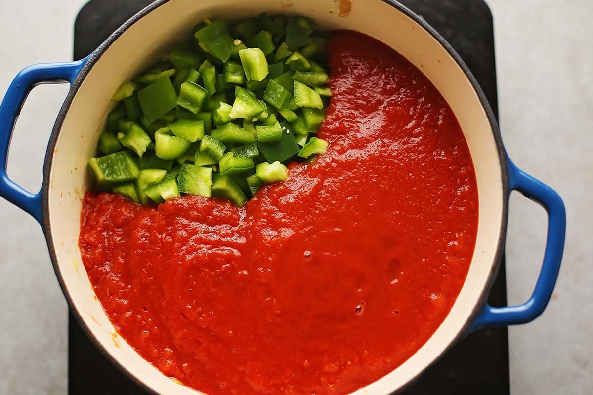 dutch oven pot with tomato sauce and diced green bell peppers