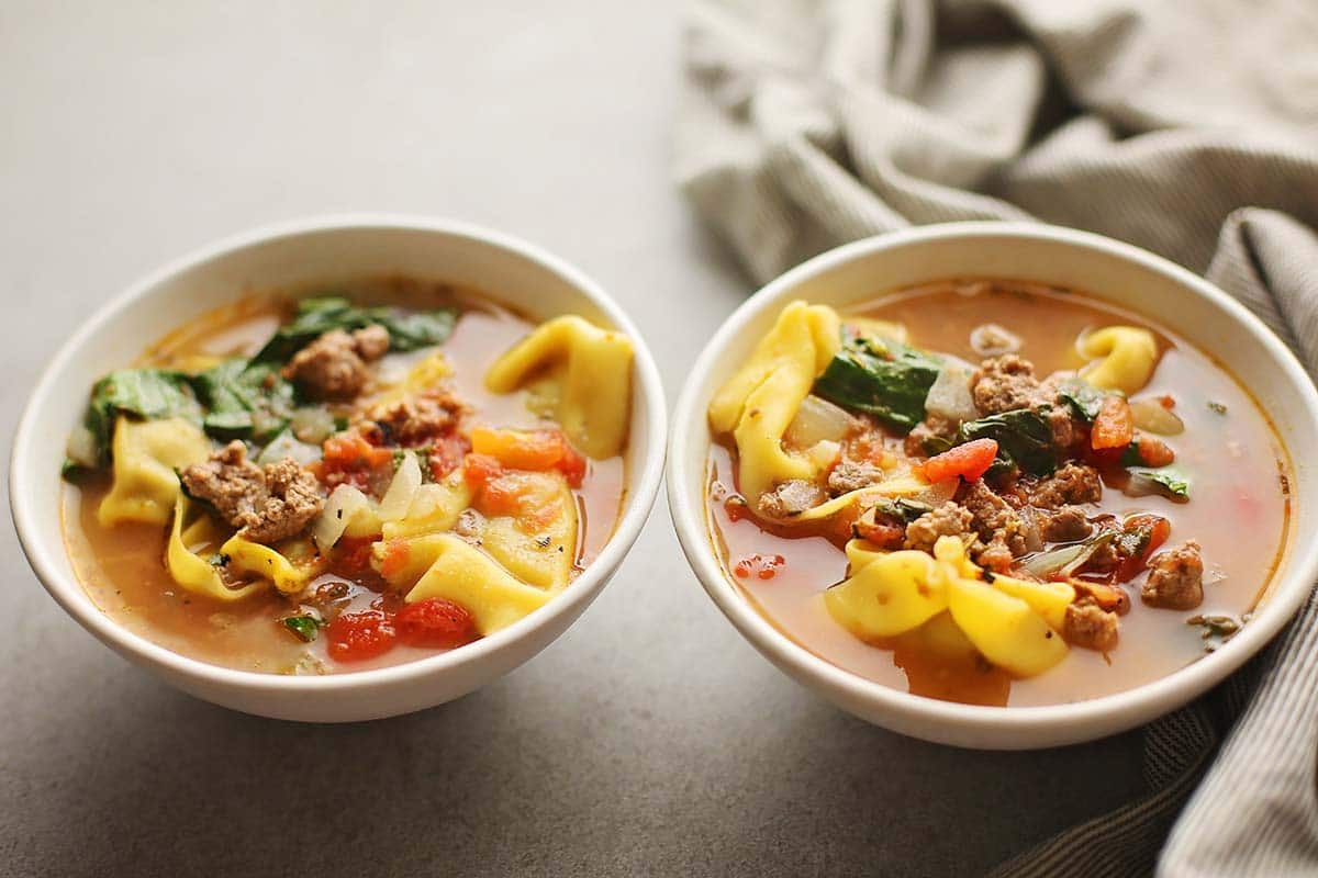 two bowls filled with soup with tortellini