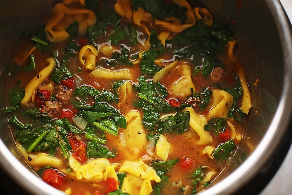 instant pot with cooked tortellini and leafy greens