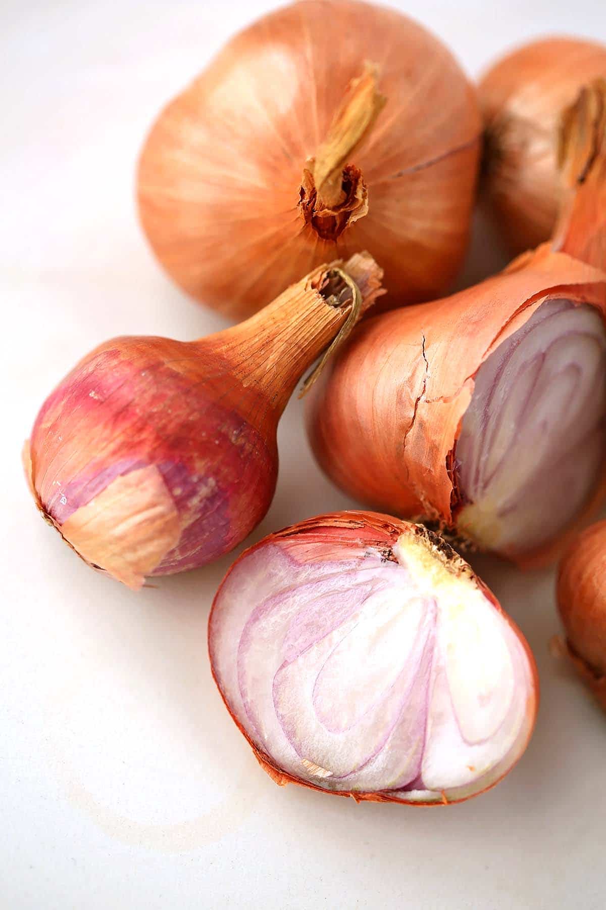 Tabletop with shallot onions, some sliced in half. 