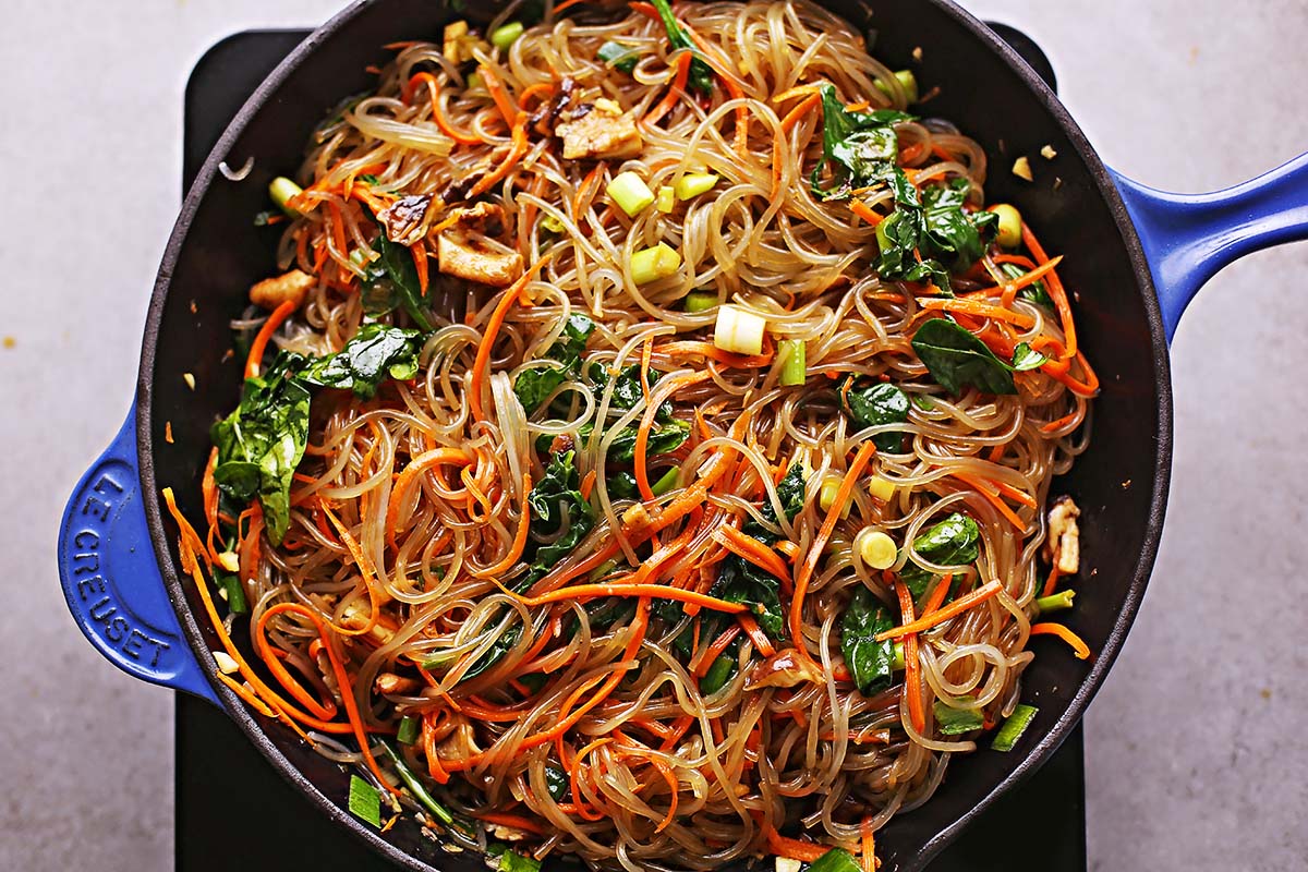 cast iron skillet with cooked Japchae noodles and colorful vegetables. 