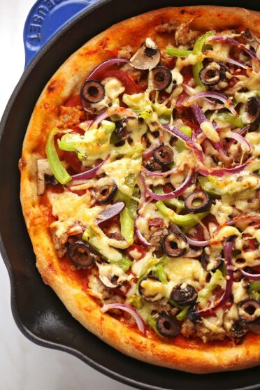 close up photo of pizza with pepperoni, bell peppers, cheese and black olives