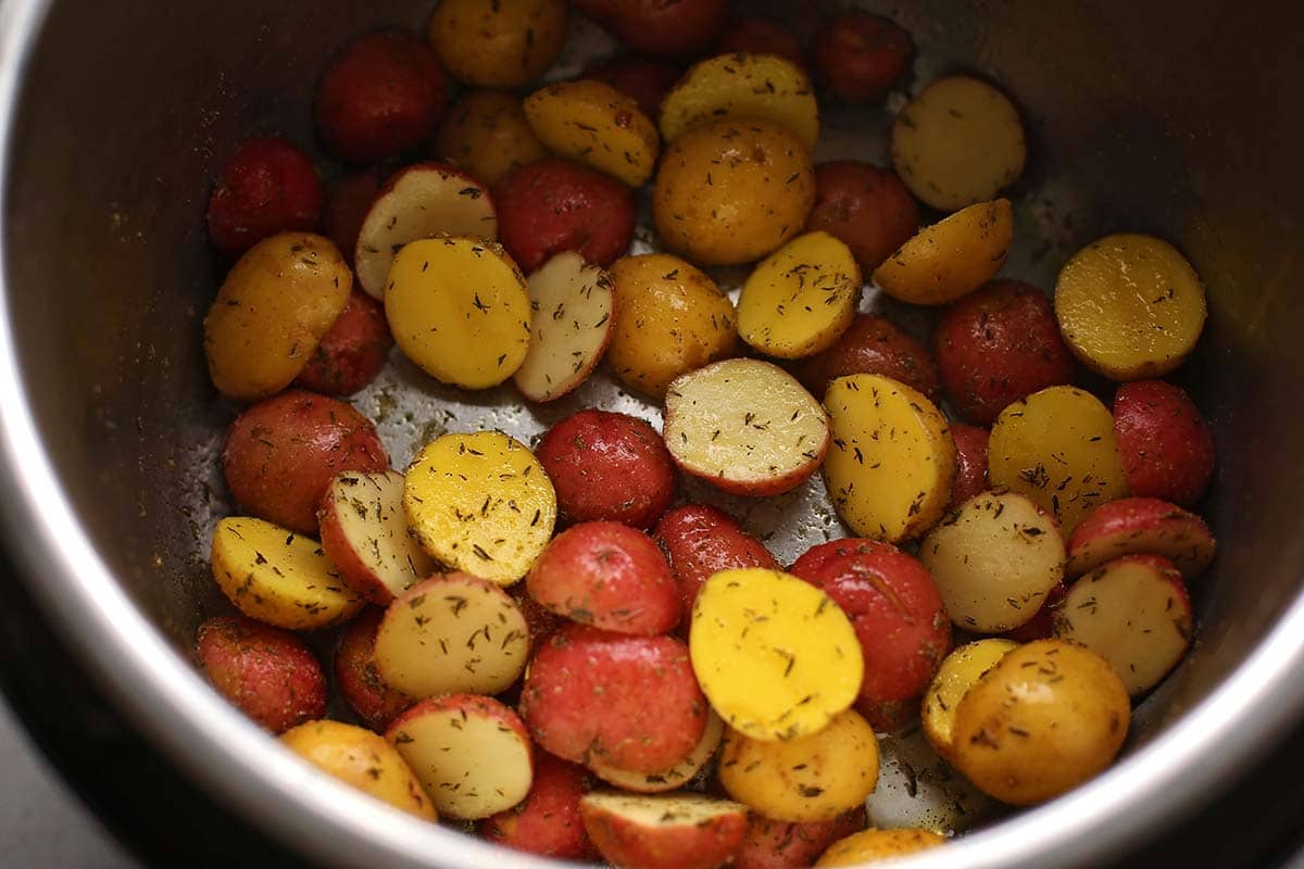 Instant Pot insert with uncooked sliced baby potatoes and spices