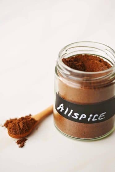 glass jar filled with dark brown spice powder with label "allspice"