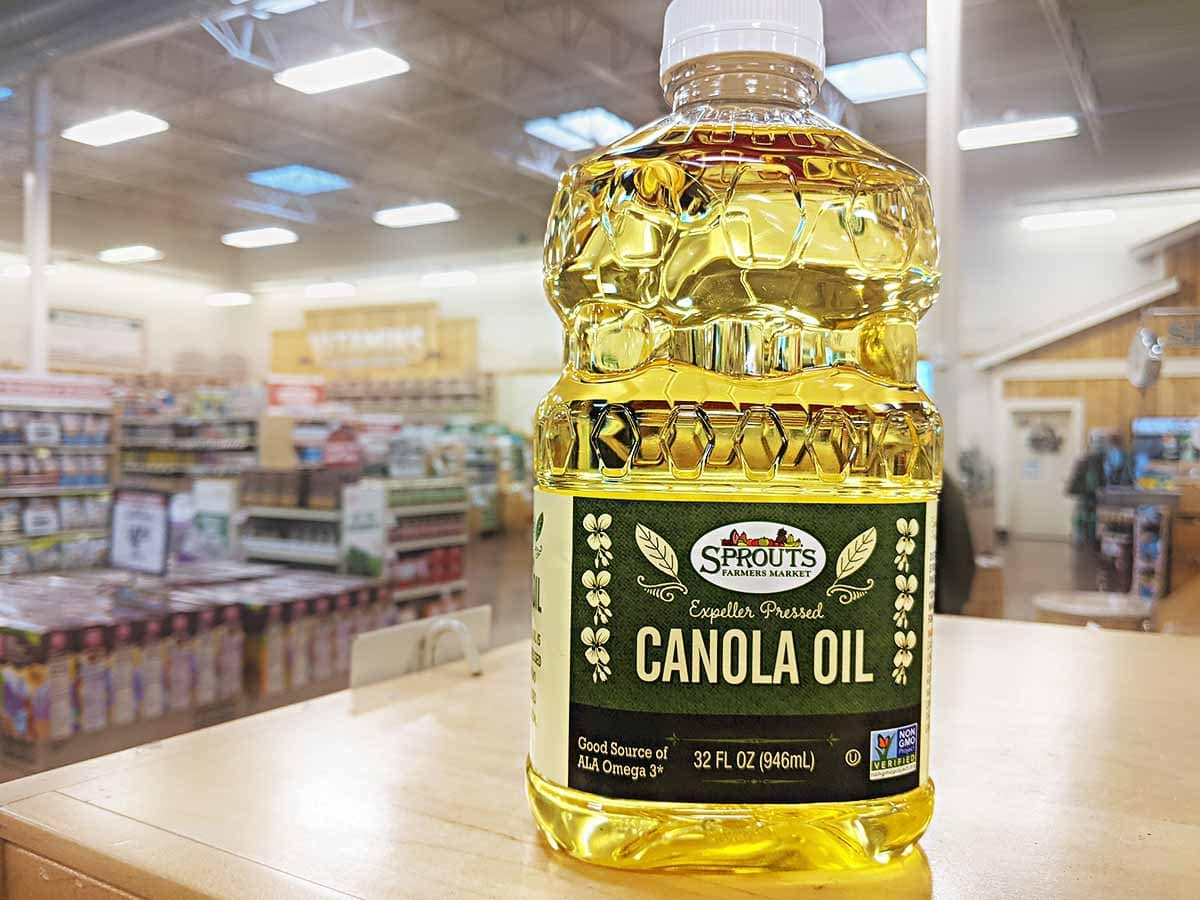 yellow-colored bottle of canola oil displayed on the shelf at the grocery store 