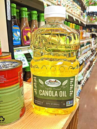 bottle filled with canola oil on the shelf at the grocery store.