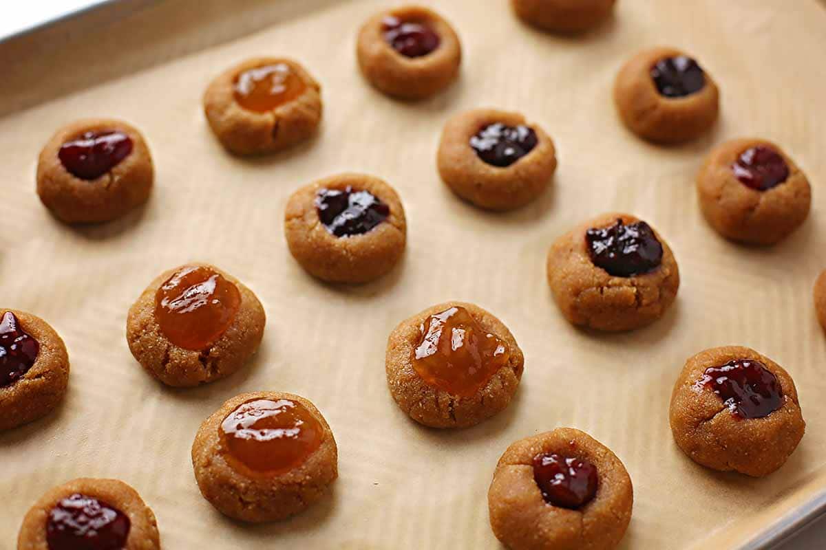unbaked cookies filled with jam inside baking sheet pan  