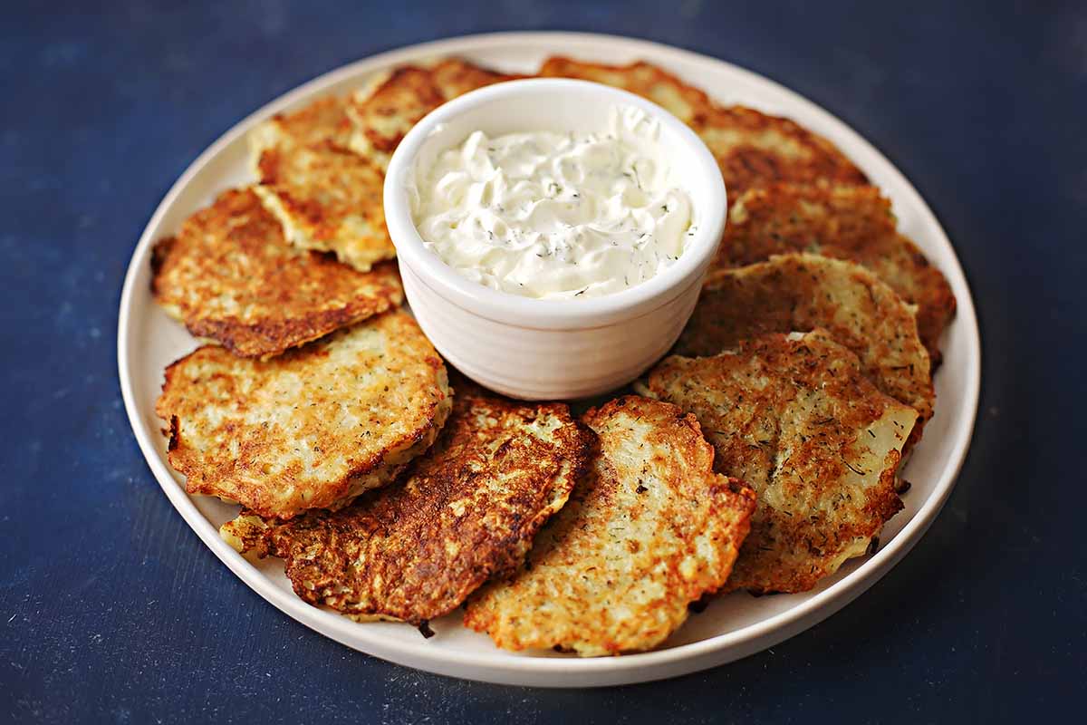 serving dish with cooked potato pancakes with small dish in the middle filled with sour cream 
