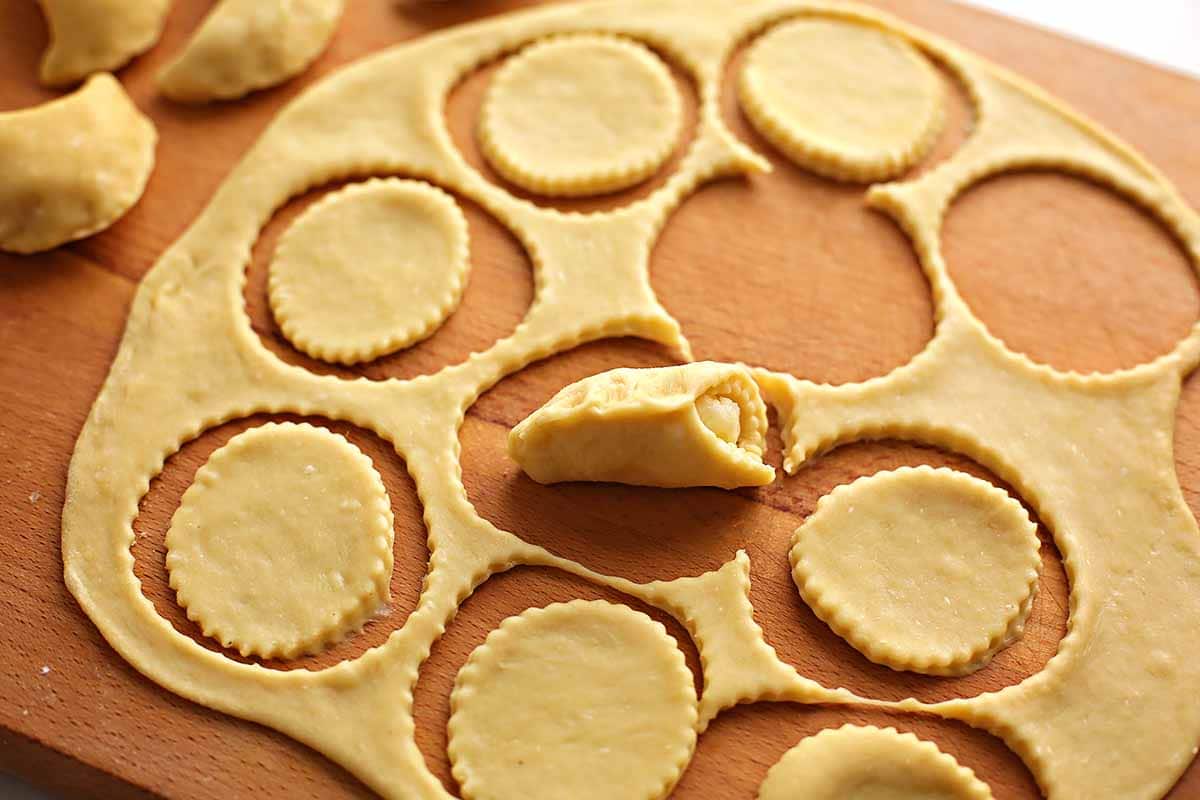 the process of making homemade vareniki, cut out circle with potato filling in the middle and pinched dough ends