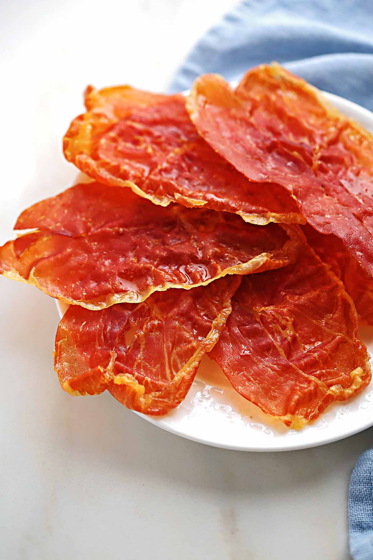 white serving plate with cooked prosciutto slices 