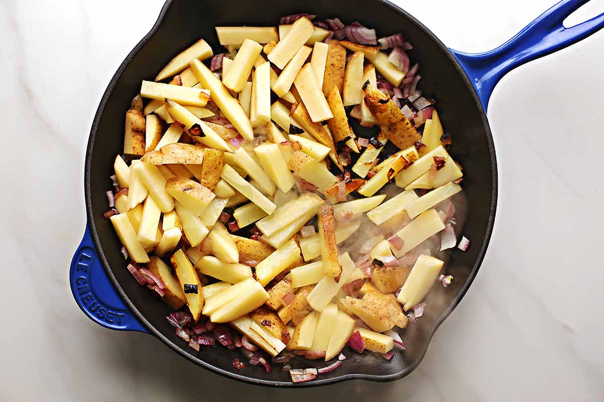 skillet with sliced uncooked potatoes 