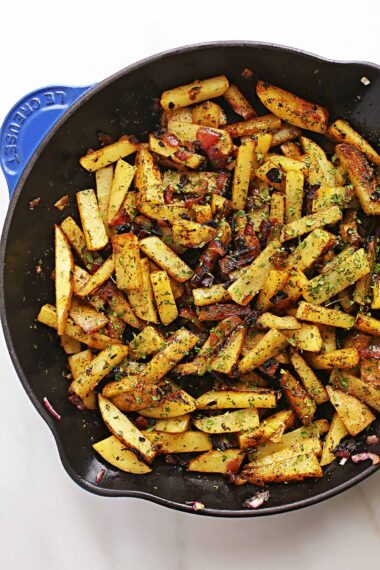 skillet with fried potatoes sprinkled with green seasoning