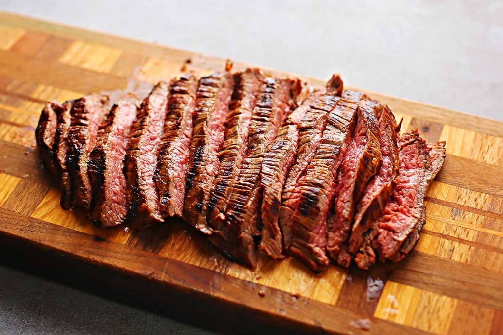 cutting board with sliced flank steak cooked medium raw