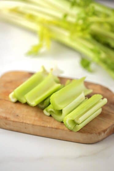 wooden cutting board with sliced green celery stalks