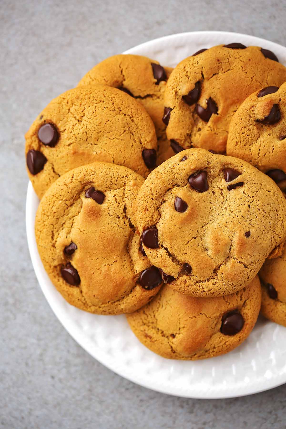 white serving plate with several baked cookies with chocolate chips