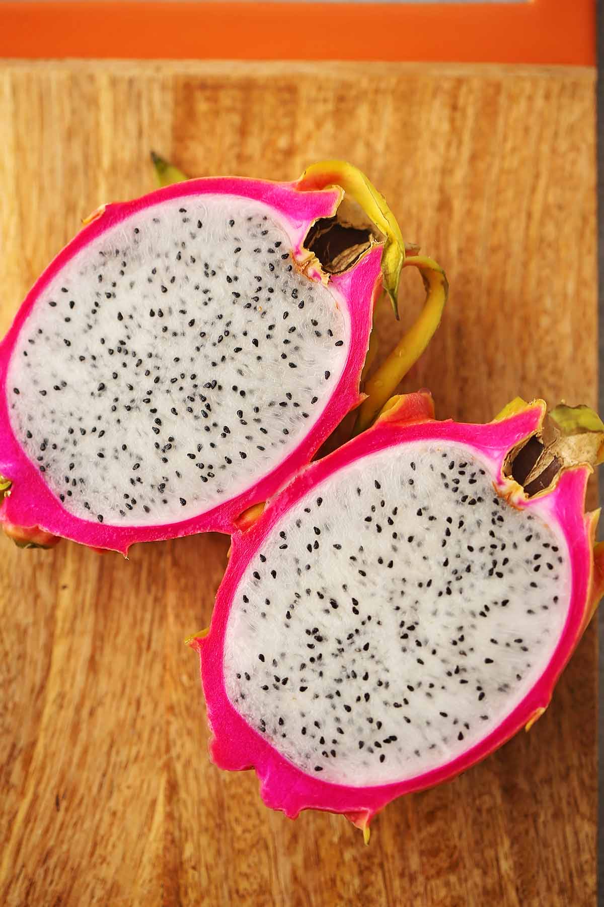 cutting board with sliced in half dragon fruit with white flesh