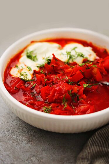white bowl filled with red soup with cabbage and beets