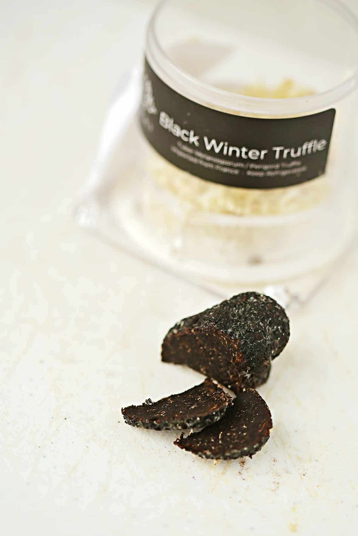white table top with sliced black truffle and jar labelled black winter truffle