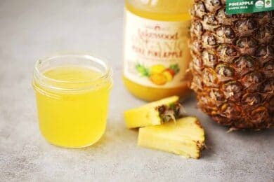 glass jar filled with pineapple juice, sliced and whole pineapple, glass bottle with juice