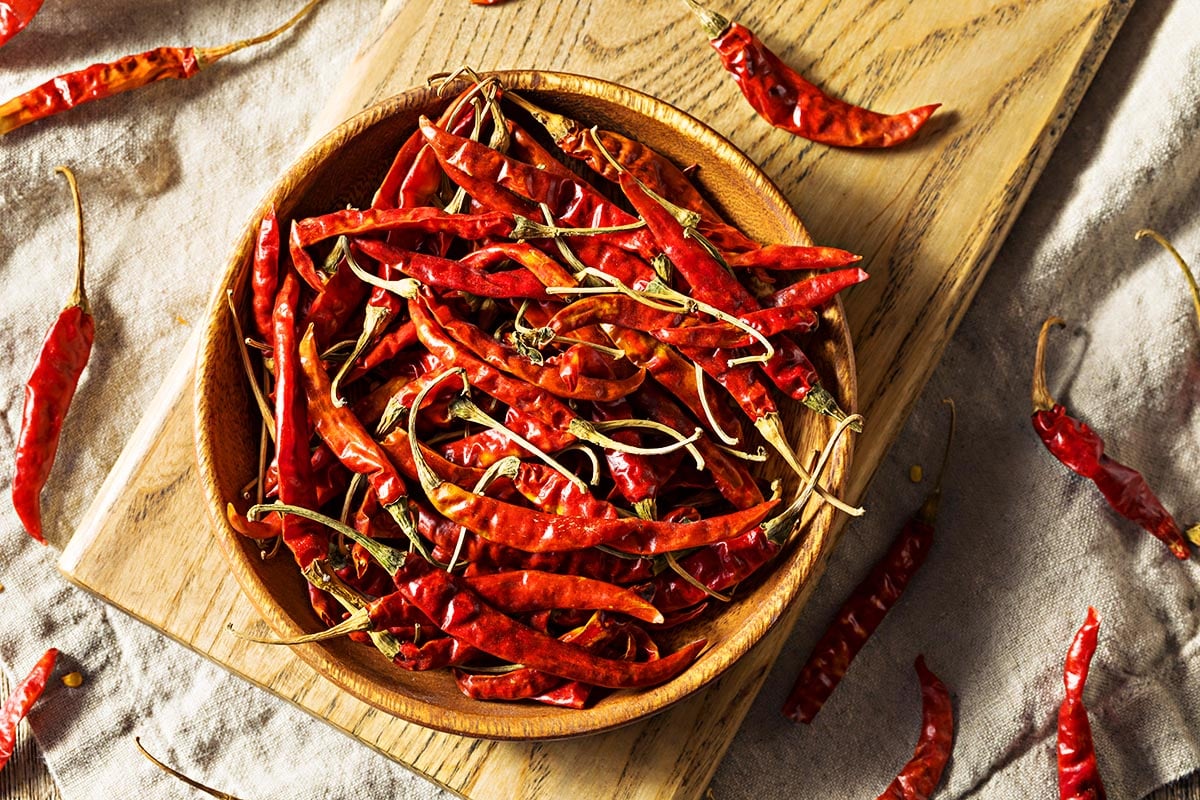 wooden bowl filled with Chile De Arbol Peppers. 