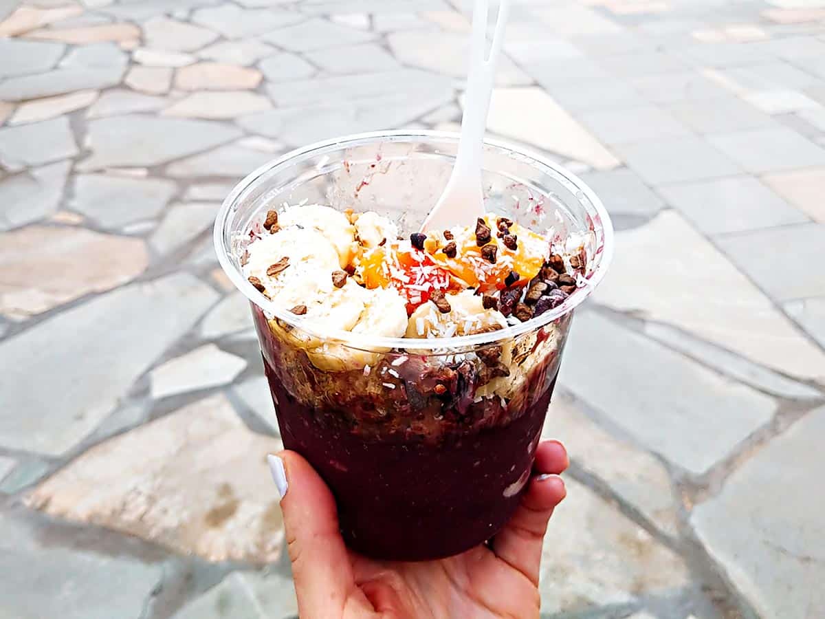 Cup filled with acai and sliced fruits. 