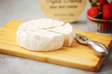 wooden cutting board with goat cheese wheel