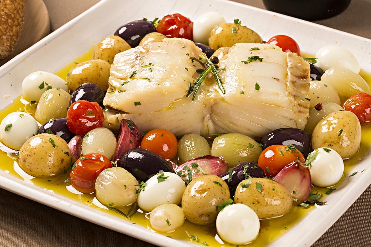 serving plate with cooked cod with potatoes and olives