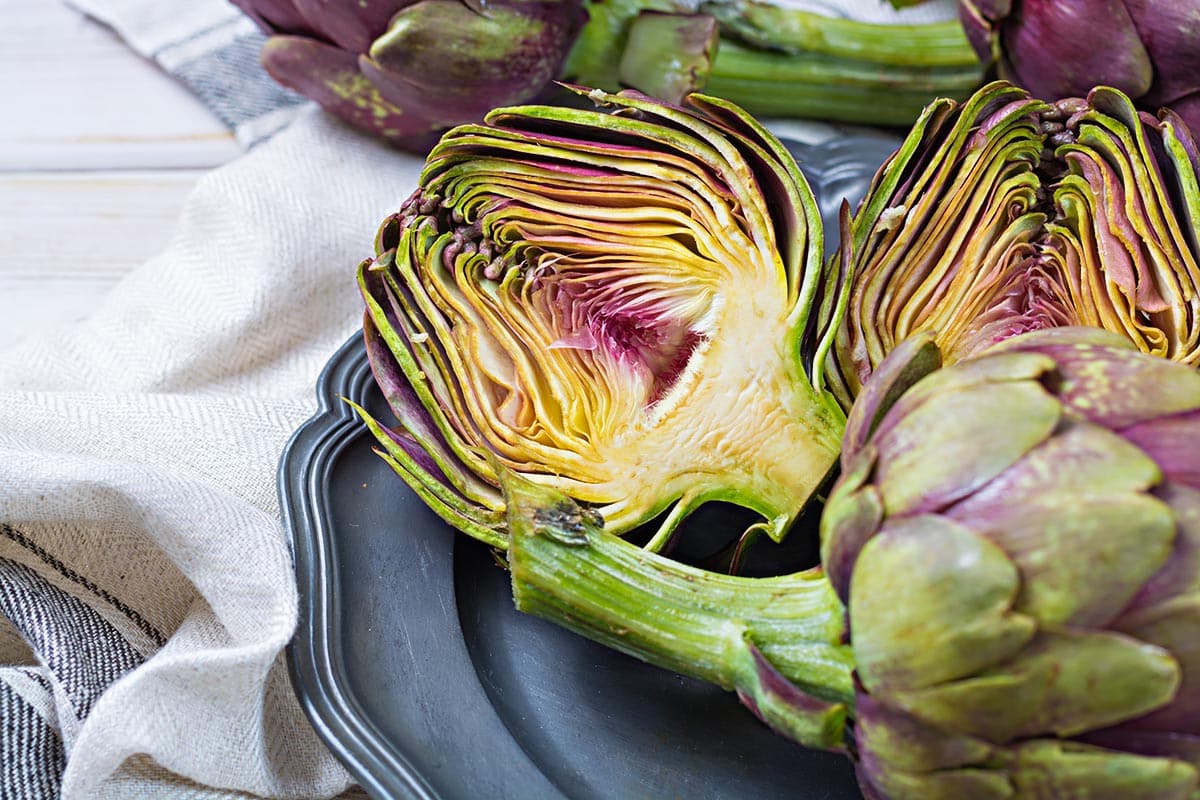Plate with sliced fresh artichoke showing bright pink center.