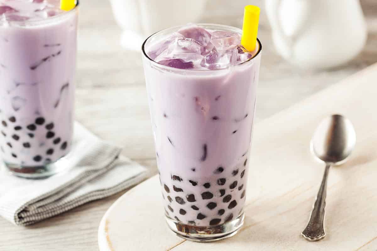 Tall glass filled with purple boba tea with milk