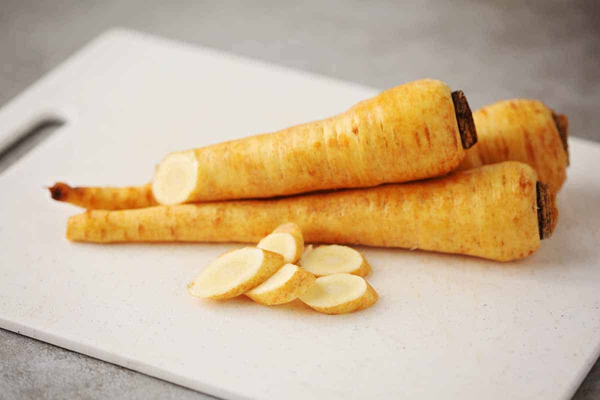 white cutting board with fresh parsnips.