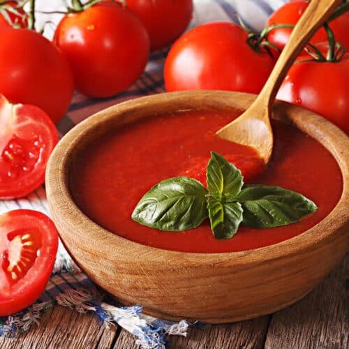 bowl filled with tomato passata with fresh tomatoes next to it.