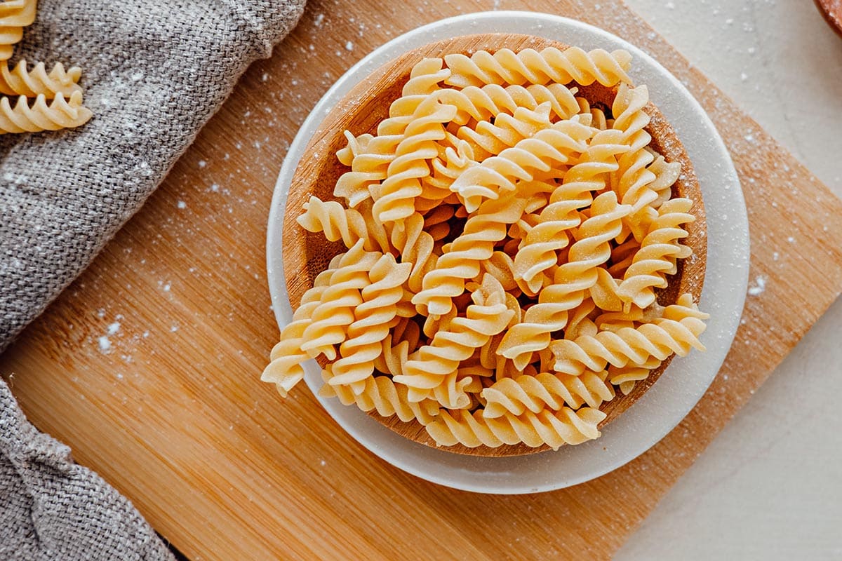 white dish filled with uncooked fusilli and rotini pasta