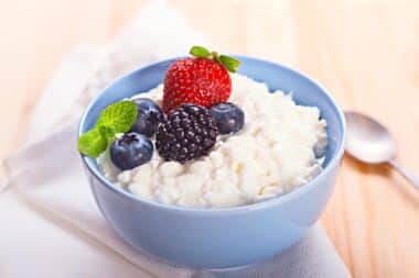 Blue bowl filled with cottage cheese and topped with fruits.