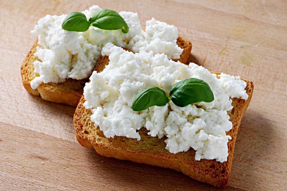two toasts topped with cottage cheese and fresh herbs. 